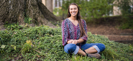 Gia Hast '24 sitting under a tree.